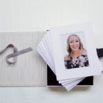 Matted prints in a open portrait photo box. The photo on top shows a blonde woman in her 30s smiling at the camera.