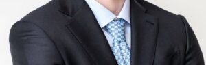 Light blue patterned tie paired with blue shirt and dark jacket
